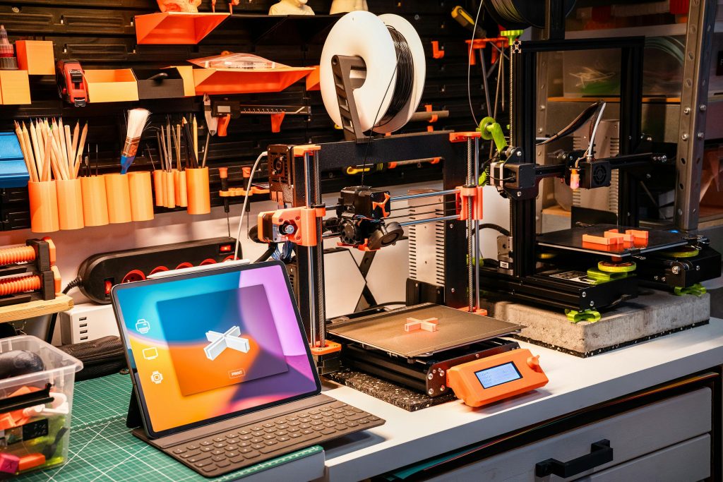 Ein Hightech-Workshop mit 3D-Druckern und einem Tablet auf einem Schreibtisch, der moderne Innovation zeigt.